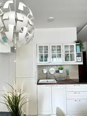 a kitchen with white cabinets and a sink and a chandelier at Apartmani Madera in Kopaonik