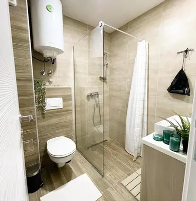 a bathroom with a toilet and a glass shower at Apartmani Madera in Kopaonik
