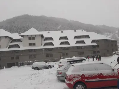 a snow covered building with cars parked in the snow at Bele staze 59 in Brus