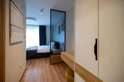 a room with a mirror and a bedroom with a bed at Omega Apartments in Vrnjačka Banja