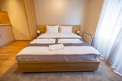 a bedroom with a large bed with white sheets at Omega Apartments in Vrnjačka Banja