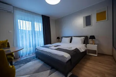 a bedroom with a bed and a table and a window at Omega Apartments in Vrnjačka Banja