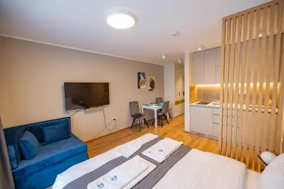 a hotel room with a bed and a blue couch at Omega Apartments in Vrnjačka Banja