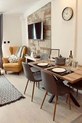 a dining room with a table with chairs and a clock on the wall at Kopaonik Milmari Apartment N95 in Kopaonik