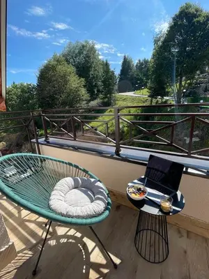 a balcony with a laptop on a table with a cushion at Kopaonik Milmari Apartment N95 in Kopaonik