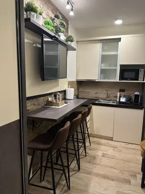 a kitchen with a bar with chairs and a sink at Apartman Šmizla N lux - Milmari Resort in Kopaonik