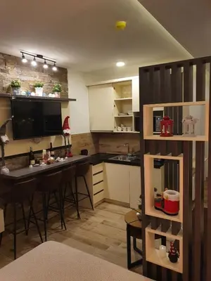 a kitchen with a bar with chairs and a table at Apartman Šmizla N lux - Milmari Resort in Kopaonik