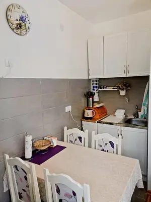 a kitchen with a table with chairs and a clock on the wall at Vidikovac in Vrnjačka Banja