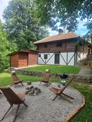 a patio with two chairs and a grill in front of a cabin at Vikendica Bajka in Despotovac