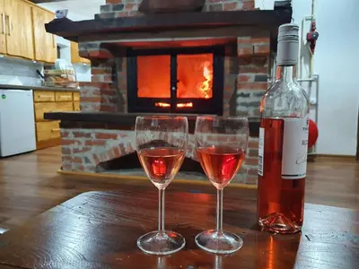 two glasses of wine sitting on a table with a bottle at Vikendica Bajka in Despotovac