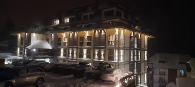 a lit up building with cars parked in front of it at Apartman M&S - Zoned 2 in Kopaonik