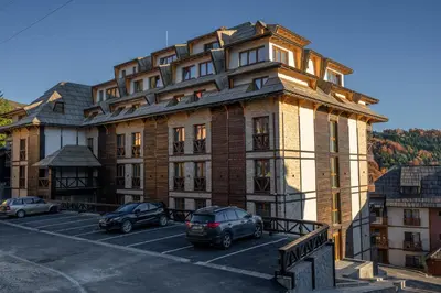 a large building with cars parked in a parking lot at Vista47 Zoned II Kopaonik in Kopaonik