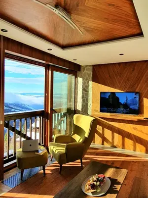 a living room with a balcony with a television and a chair at Vista47 Zoned II Kopaonik in Kopaonik