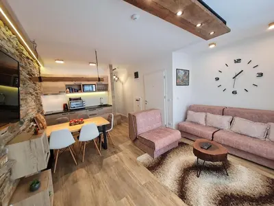 a living room with a couch and a clock on the wall at Lux Apartman Lucky in Kopaonik