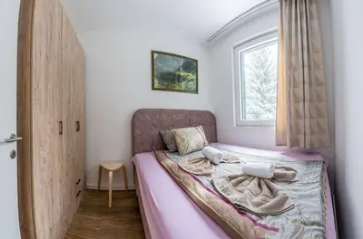 a bedroom with a bed with pink sheets and a window at Lux Apartman Lucky in Kopaonik