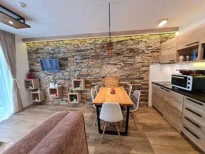a dining room with a table and a brick wall at Lux Apartman Lucky in Kopaonik