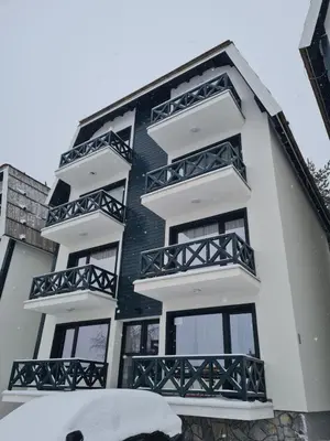 a black and white building with snow on the ground at Lux Apartman Lucky in Kopaonik