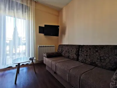 a living room with a couch and a table and a window at Jolly Kop - Apartman 4 in Kopaonik