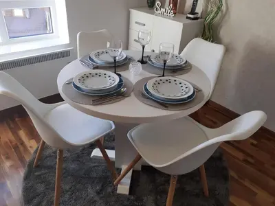 a white table with chairs and plates and wine glasses at Lux apartmani Dunja Kopaonik Čardaci - WHITE in Kopaonik