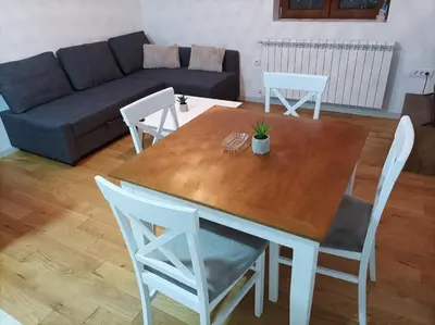 a living room with a wooden table and chairs at Apartman 8 Extra Vrnjacka Banja in Vrnjačka Banja