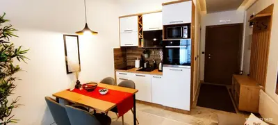 a small kitchen with a red table and chairs in a room at SANS Lux Apartman N42 Milmari Kopaonik in Kopaonik