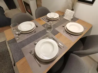 a wooden table with plates and wine glasses on it at SANS Lux Apartman N42 Milmari Kopaonik in Kopaonik