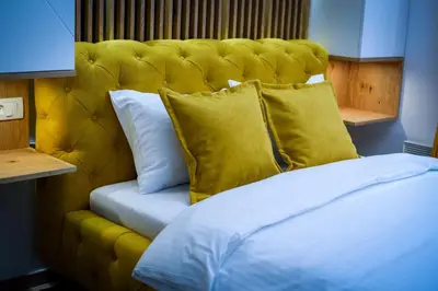 a bed with a yellow padded headboard and pillows at PleasureLUX MILMARI in Kopaonik