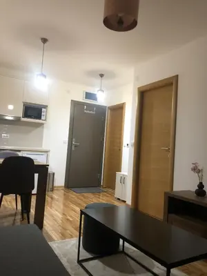 a living room with a table and a door at Apartman Kraljevi čardaci Makica Kopaonik sa garazom in Kopaonik