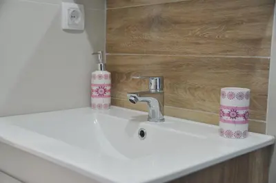a sink with a faucet and two cups on it at Apartmani Krstojević Kopaonik in Kopaonik