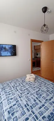a bedroom with a bed with a blue and white comforter at Apartman MonTanja Kopaonik, u hotelu Kraljevi Čardaci in Kopaonik