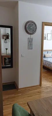 a clock on a wall in a room with a mirror at Apartman MonTanja Kopaonik, u hotelu Kraljevi Čardaci in Kopaonik
