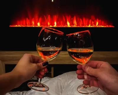 two people holding up wine glasses in front of a fireplace at MIR i LIRA apartmani Kopaonik in Kopaonik