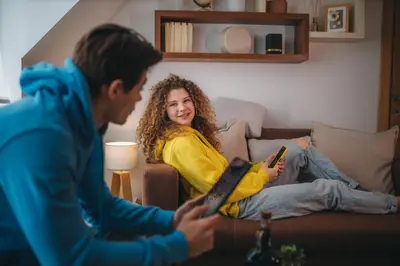 a man and a woman sitting on a couch with their computers at MIR i LIRA apartmani Kopaonik in Kopaonik