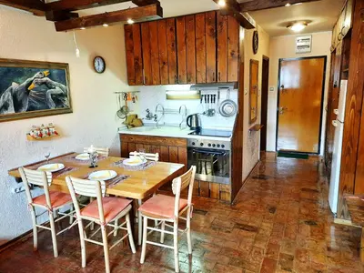 a kitchen with a wooden table and chairs and a kitchen with a stove at Apartman Pod bregom - Gondola 180m in Brzeće