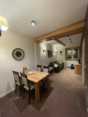 a dining room and living room with a table and chairs at Luna Apartman, Župa Kopaonik in Kopaonik