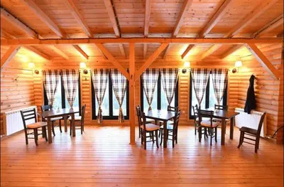 a dining room with tables and chairs and windows at Luna Apartman, Župa Kopaonik in Kopaonik