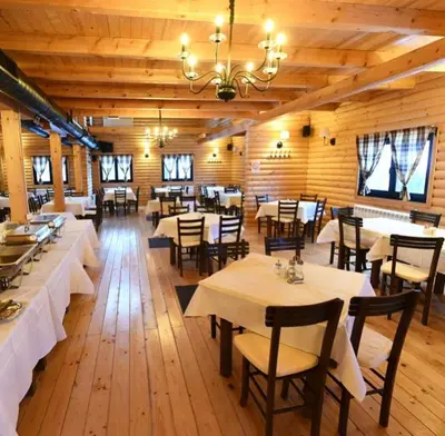 a restaurant with tables and chairs and a chandelier at Luna Apartman, Župa Kopaonik in Kopaonik