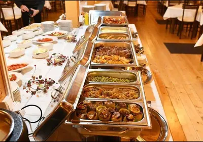 a buffet line with many trays of food on a table at Luna Apartman, Župa Kopaonik in Kopaonik