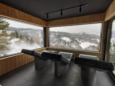 a room with two benches in front of a large window at Apartman Snesko Zoned in Kopaonik