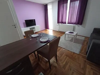 a dining table and chairs in a living room at Sunny apartment in Niš
