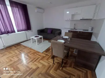a kitchen and living room with a table and a couch at Sunny apartment in Niš