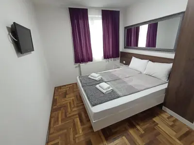 a small bedroom with a bed and a tv at Sunny apartment in Niš