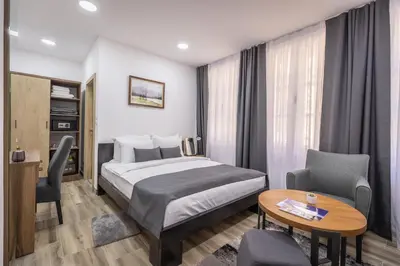 a hotel room with a bed and a table and chairs at Vila Greta by Hotel Ramonda in Rtanj