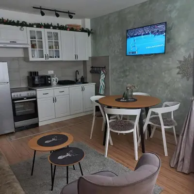a kitchen with a table and chairs and a tv on the wall at Pogled iznad oblaka in Kopaonik