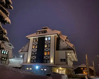 a building with snow on top of it at night at Apartman Sky View, Župa Wellness & Spa u Centru Kopaonika in Kopaonik