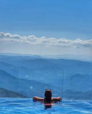 a woman in a swimming pool looking at the mountains at N-delux apartman in Kopaonik