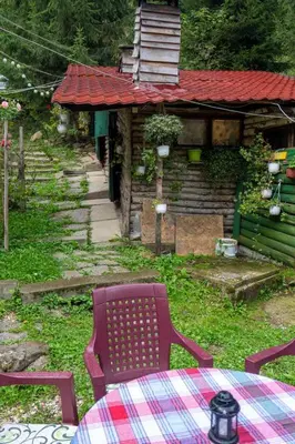 a table and a chair in front of a house at Zimska idila in Crni Vrh