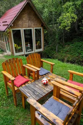 a wooden picnic table with two chairs and a cabin at Zimska idila in Crni Vrh
