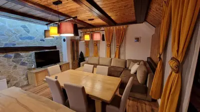 a dining room and living room with a table and a couch at Ski House in Kopaonik