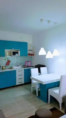 a kitchen with blue cabinets and a white table and chairs at Apartman Ivanovic 6 Sokobanja in Soko Banja